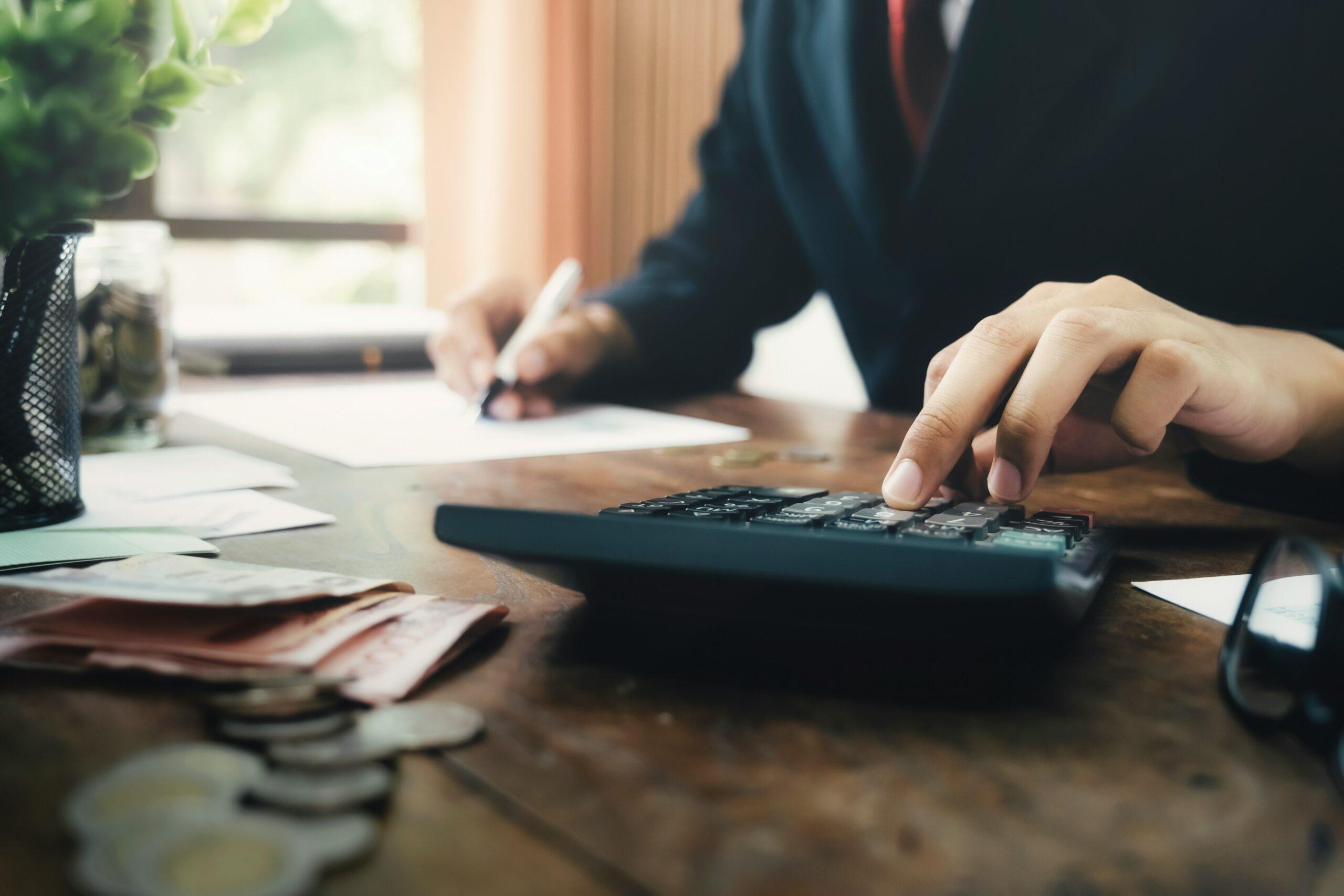A man in a suit calculates money using a calculator, focused on his financial assessment.